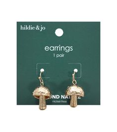 a pair of earrings with gold colored mushrooms on them in front of a green box