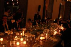 a group of people sitting around a dinner table with candles on the dining room table