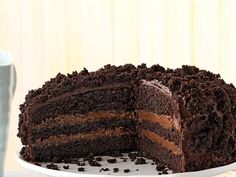 a chocolate cake on a white plate with one slice cut out and ready to be eaten