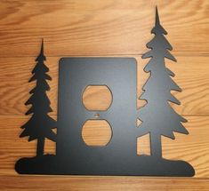 a metal sign with trees on it and a light switch cover in the shape of a house