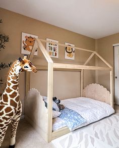 a giraffe standing next to a bed in a child's room with white walls