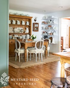 the dining room table is set with white chairs and dishes on shelves in the background