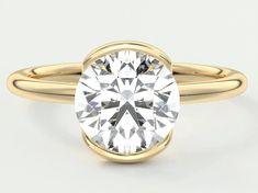 a yellow gold engagement ring with a round cut diamond in the center, on a white background