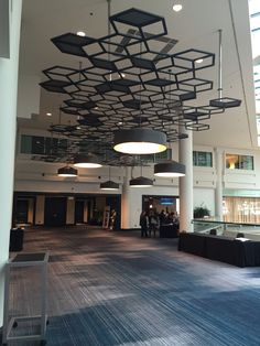 an empty lobby with people walking around and chandeliers hanging from the ceiling above