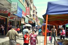 many people are walking down the street with umbrellas