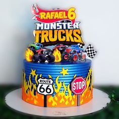 a birthday cake with monster trucks on top is decorated like a fire truck and flames