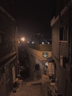 an alley at night with the city lights in the background