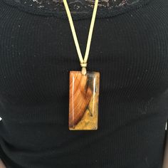 a woman wearing a necklace with a wooden pendant on it's end and a yellow cord