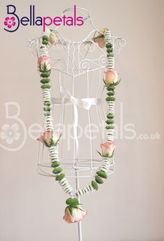 a white mannequin with pink roses and green beads