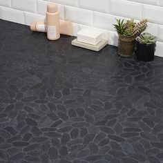 a black counter top in a bathroom next to a plant and soap dispenser