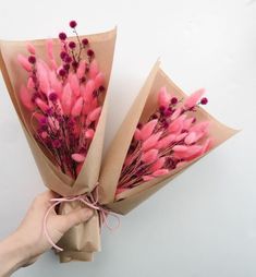 someone is holding some pink flowers wrapped in brown paper