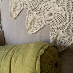 a crocheted doily is hanging on the back of a couch with a green pillow