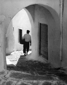 a man is walking down an alley way in black and white with the door open