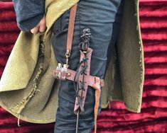 a person wearing leather pants and holding a cross on their back with chains attached to them