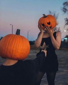 two people with pumpkins on their heads, one is holding the other's head