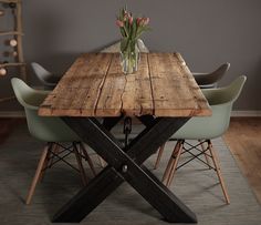 a wooden table with chairs around it and flowers in a vase on the table top