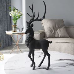 a black deer figurine stands on a marble coffee table