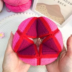 a person holding a pink and red knitted object