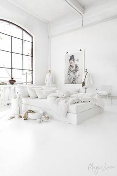 a living room with white furniture and large windows