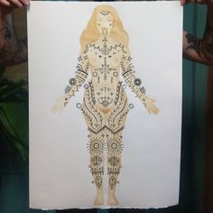 a person holding up a drawing of a woman with many body parts on her chest