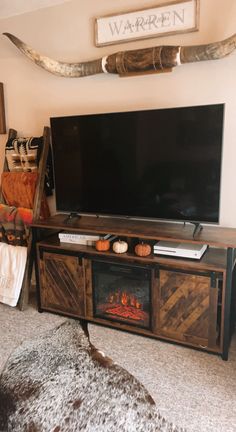 a flat screen tv sitting on top of a wooden entertainment center next to a fire place