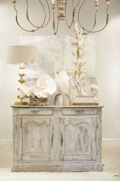 an old dresser with flowers and candles on top is displayed in a white living room