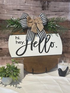 a wooden sign that says hi hey hello with a bow on it and some potted plants