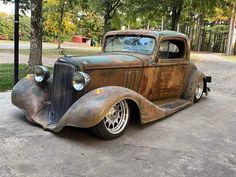 an old, rusted car is parked in the driveway