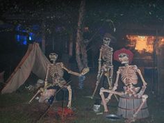 two skeletons sitting on top of a barrel in front of a tent at night time