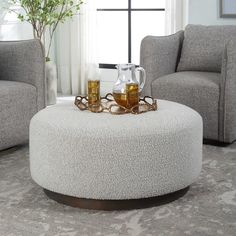 a coffee table sitting on top of a white ottoman in a living room next to two chairs