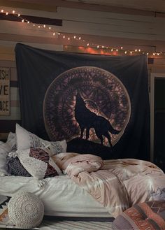 a wolf tapestry hanging over a bed in a room with string lights on the ceiling