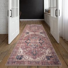 an old rug is on the floor in front of two white doors and a black wall