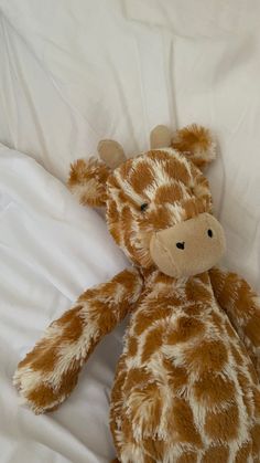 a stuffed giraffe laying on top of a bed