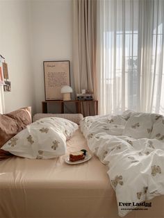 an unmade bed with two pillows on top of it and a piece of cake on the bottom