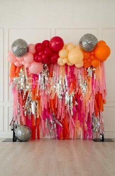 an assortment of balloons and streamers are on display in front of a white wall