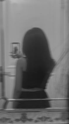 a woman standing in front of a mirror with her back to the camera