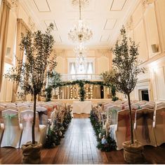 the ceremony room is decorated with white linens and green trees