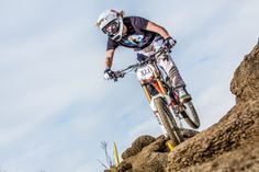 a man riding a dirt bike on top of a rocky hill