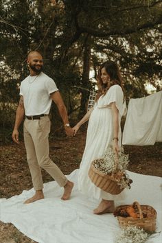 a man and woman holding hands while standing on a blanket