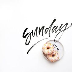 two doughnuts sitting on top of a plate with the word sunday written behind them