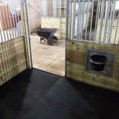 an open barn door with a wheelbarrow in the center and horse stalls behind it