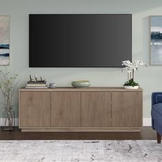 a large flat screen tv mounted to the side of a wooden cabinet in a living room