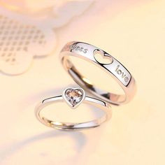 two silver rings with heart and love written on the sides, one has a diamond in the middle