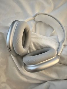 a pair of headphones laying on top of a white sheet covered bed with sheets