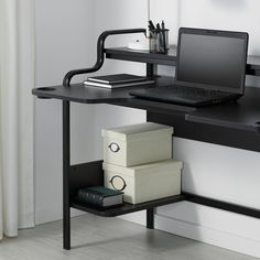 a laptop computer sitting on top of a black desk next to a stack of boxes