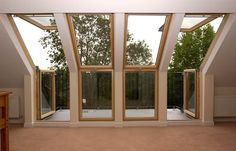 an empty room with three large windows overlooking trees