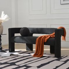 a black bench sitting on top of a rug next to a vase filled with flowers