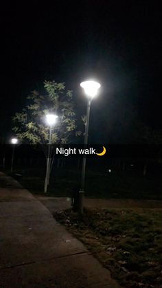 the night walk is lit up with street lights and trees in the background at night