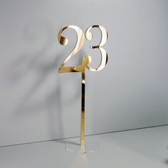 a gold cake topper with the number twenty eight on it's side, standing in front of a white wall