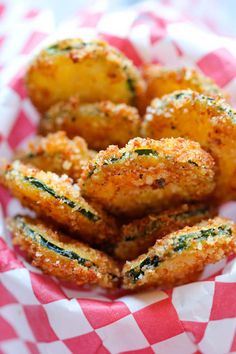 some fried food is in a basket on a checkered table cloth with red and white napkins